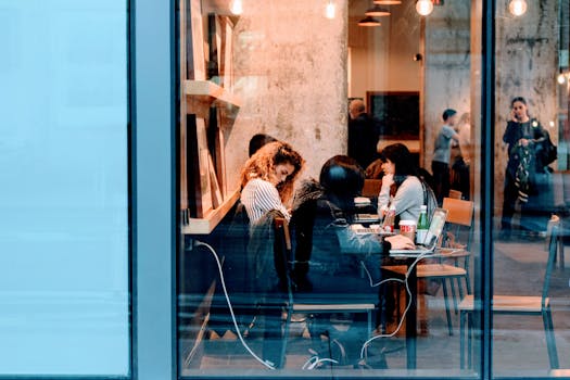 Group of adults working inside a stylish city cafe, showcasing modern work culture.
